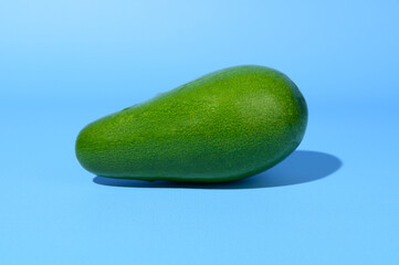 Avocado fruit with green, uneven skin and tough shadow underneath