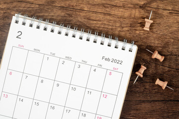 Top view Calendar desk 2022 on February month, The concept of planning and deadline with push pin on wooden table background.