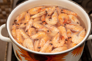 Red shrimps are boiled in a saucepan.