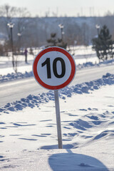 Speed limit sign 10 on the road in the snow.