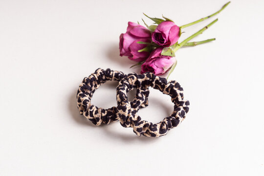 Soft elastic bands for hair and small pink roses on background. Hair clips with leopard print 