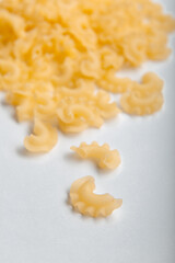Side view of raw creste di gallo pasta on a white background