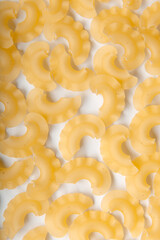 Symmetrical top photo of raw creste di gallo pasta on white background