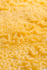 Background of various raw kinds of pasta closeup. Uncooked food background or texture close up