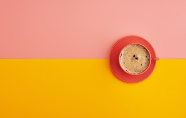 Top view of a cup of coffee on orange pastel background