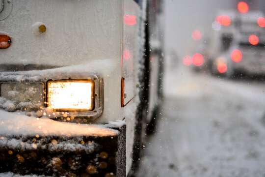 Winter snow on the streets, focus on a bus headlight close up.