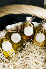 Four glass bottles of olive oil with different flavors: hot pepper, rosemary, lemon, garlic and turmeric in a gift box