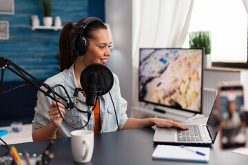 Woman in home studio recording podcast with mobile phone. Vlogger using headphones, microphone and...