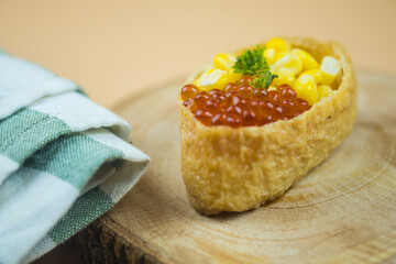 Fried tofu stuffed with rice and topping with fish roe and corn