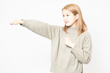 パンチのジェスチャーをするセーターを着た若い女性 - obrazy, fototapety, plakaty