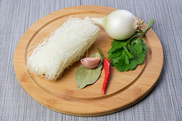 Dry funchose and ingredients for preparing an Asian dish. Spices and assorted vegetables are ready to cook with Chinese glass noodles. Cooking vegetarian meals.