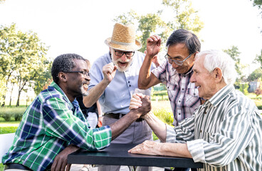 Group of senior friends playing arm wrestling at the park