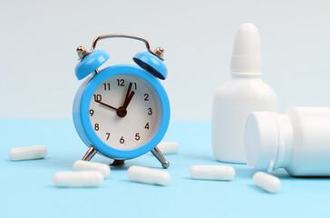On a blue and white background, a blue clock, white tablets and containers.