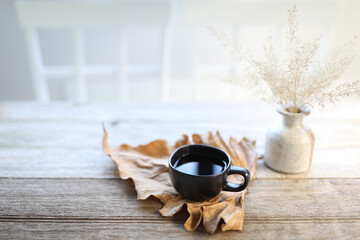 Black coffee cup on dry leaf and dry grass vase