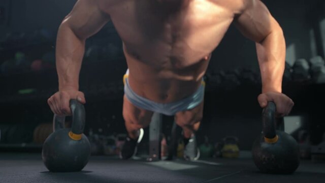 Muscular athletic young fitness man in the gym doing push-ups. Sport and health care concept