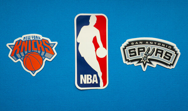October 1, 2021, Springfield, USA, Emblems of the New York Knicks and San Antonio Spurs basketball teams on a blue background.