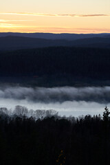 The fog is dense but the sun is cracking out. Shot in the evening from a height over Oslo city in Norway. The fog is like a blanket over the people and city.  Shot in autumn. 