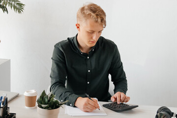 Focused young businessman calcucating numbers, productive day at the office