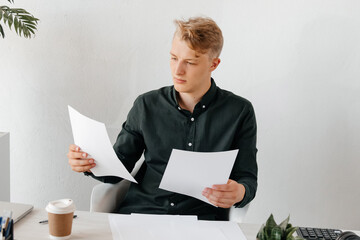Attentive young businessman comparing the documents, productive day at the office