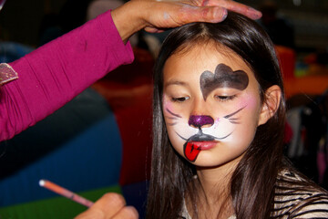 little girl with face painting on of a cat.