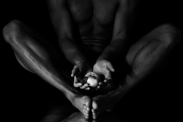 Male hands hold an apple against the background of naked legs above the mirror. Low key. Black and white photo. - obrazy, fototapety, plakaty