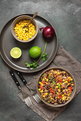 Mexican salad with black beans, corn and quinoa in a bowl on a dark grunge background. Top view.