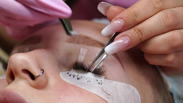 Eyelash extension procedure. Woman eye with long eyelashes. Eyelashes, close-up, macro, selective focus. 4K