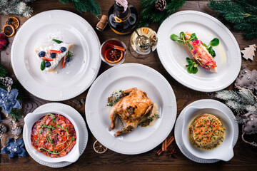 Delicious Christmas themed dinner table with roasted chicken, appetizers and desserts. Holiday concept.