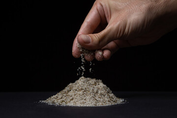 Salt mixed with spices on a black background. A man's hand takes a pinch of salt. Traditional...