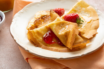 Close up of crepes with strawberry jam on plate