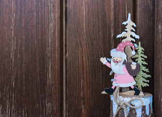 Christmas ornament with Santa Claus and firs on rustic wooden background with copy space