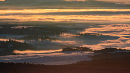 Foggy valley with cloud rolling over the hills at sunrise in winter.