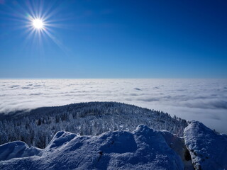 View of a snowy winter mountains, above clouds.