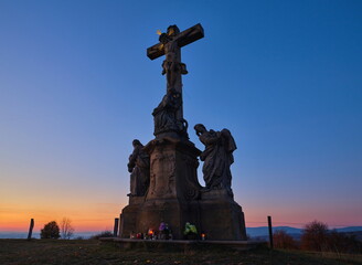 Stone christianity monument at the top of a hill at sunset.