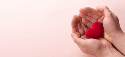 hand holding a red heart on brown background, valentine's day love close up