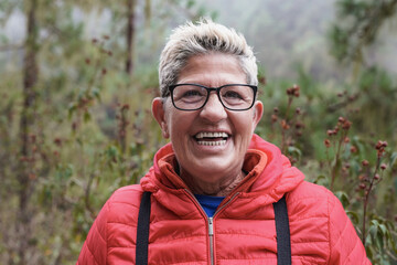 Naklejka na ściany i meble Senior woman smiling on camera during trekking day outdoor
