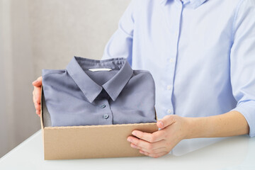 A woman unpacks a cardboard box with clothes, buys goods online, delivery concept.