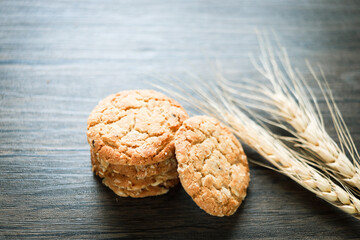 Delicious oatmeal cookies with spikelets on dark wooden table.