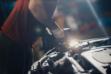 hands of a mechanic unscrew the bolts of electric wrenches, car maintenance.
