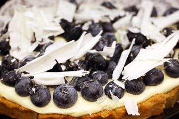 Blueberry pie with white grated chocolate, cream and fresh berries