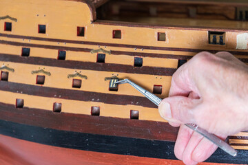 Old man working on creating a ship model