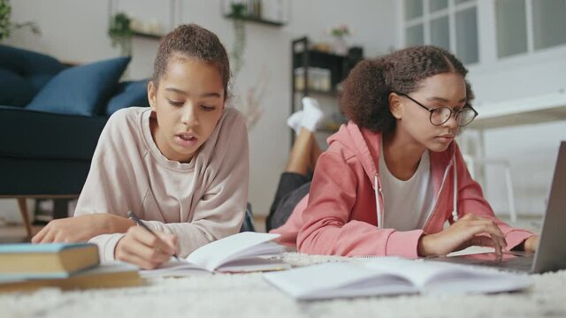 Female friends doing homework together, studying at home, school assignment