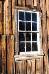 White window in a wood building with dirty glass from an angle