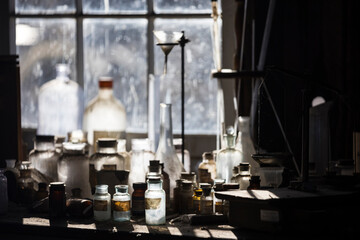 Backlit glass bottles and jugs in a dirty window