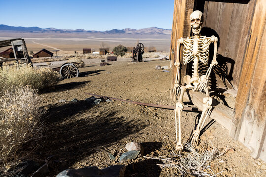 Skeleton leaning against a wall in a ghost town in the desert