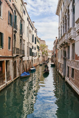 Obraz na płótnie Canvas Venice, Italy - 10.12.2021: Traditional canal street with gondolas and boats in Venice, Italy.