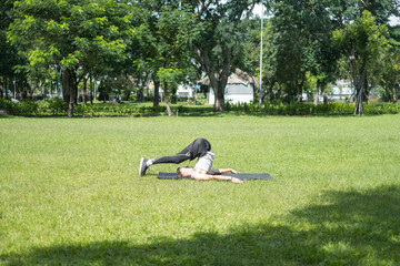 Sporty active young man in sportswear doing sport exercises in the park. Fit caucasian man stretching on the black sports mat outdoors.