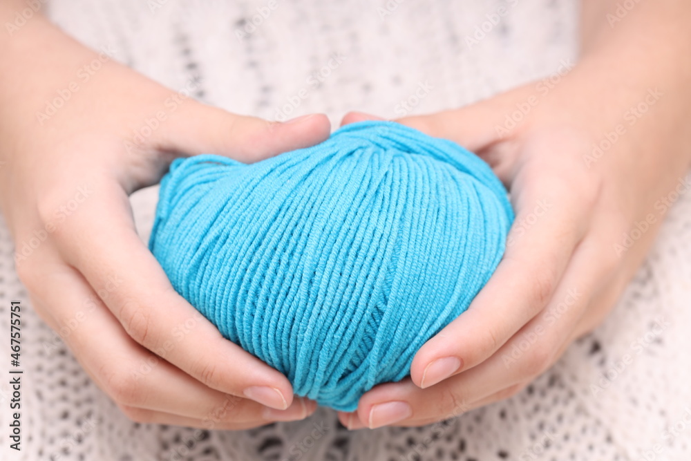 Aufkleber blue ball of wool in hands on the background of a white knitted tablecloth