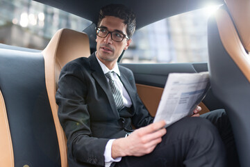 Businessman reading newspaper in car