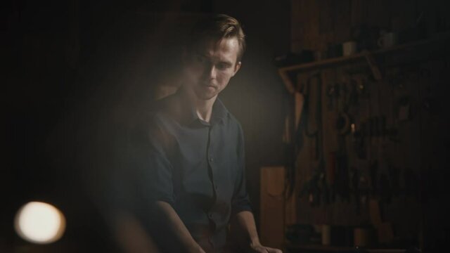 Defocused shot of professional man tailor working with fabric and pattern in his work shop, tracking shot